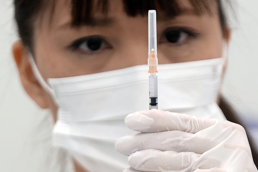 En sjuksköterska kontrollerar en dos av boostervaccinet Moderna COVID-19 vid ett vaccinationscenter i Tokyo.