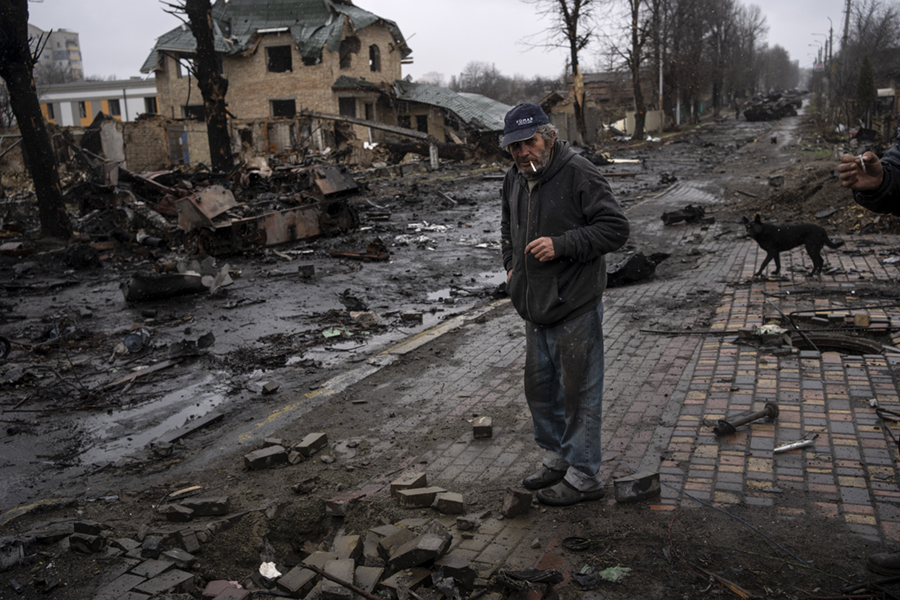 Konstyantyn, 70, röker en cigarett bland förstörda ryska stridsvagnar i Bucha, i utkanten av Kiev, Ukraina, söndagen den 3 april 2022.