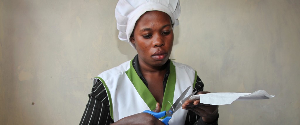 En arbetare klipper till lokalt tillverkade mensskydd i Uganda.