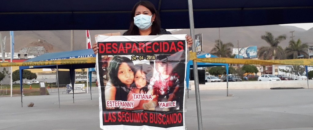 Patricia Acosta håller upp en affisch med en bild på sin dotter och de två barnbarnen Tatiana och Yamile.