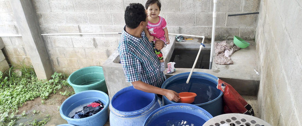 Alex Leiva hämtar vatten i en av de tunnor som han lyckats fylla genom att gå upp klockan fyra på morgonen – en av få tidpunkter då vattenkranen inte sinar.