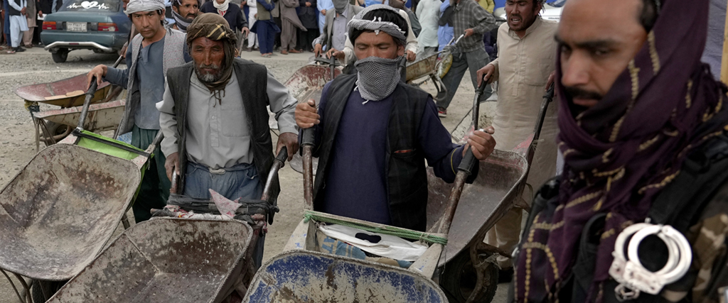 Människor får matransoner som distribueras av en Sydkoreansk NGO, samtidigt som en taliban övervakar, Kabul, Afghanistan, tisdagen den 10 maj 2022.