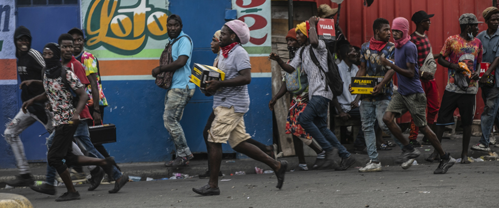 Demonstranter bär bort plundrade föremål under en protest mot bränsleprishöjningar och för att kräva att Haitis premiärminister Ariel Henry avgår,  Port-au-Prince, Haiti, fredagen den 16 september 2022.