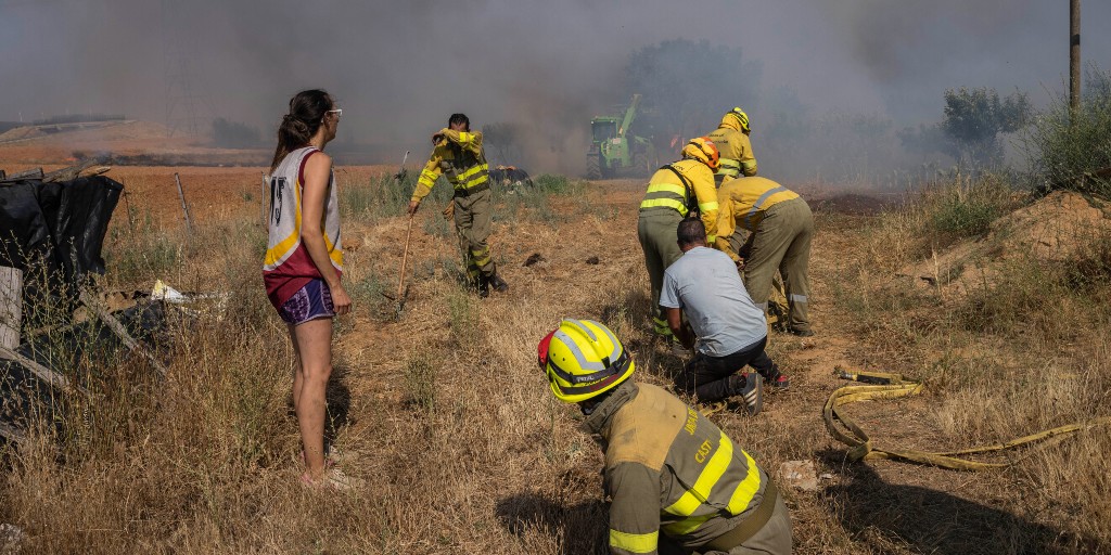 Brandkår i nordvästra Spanien i färd med att släcka en brand som letade sig närmare ett bostadshus.