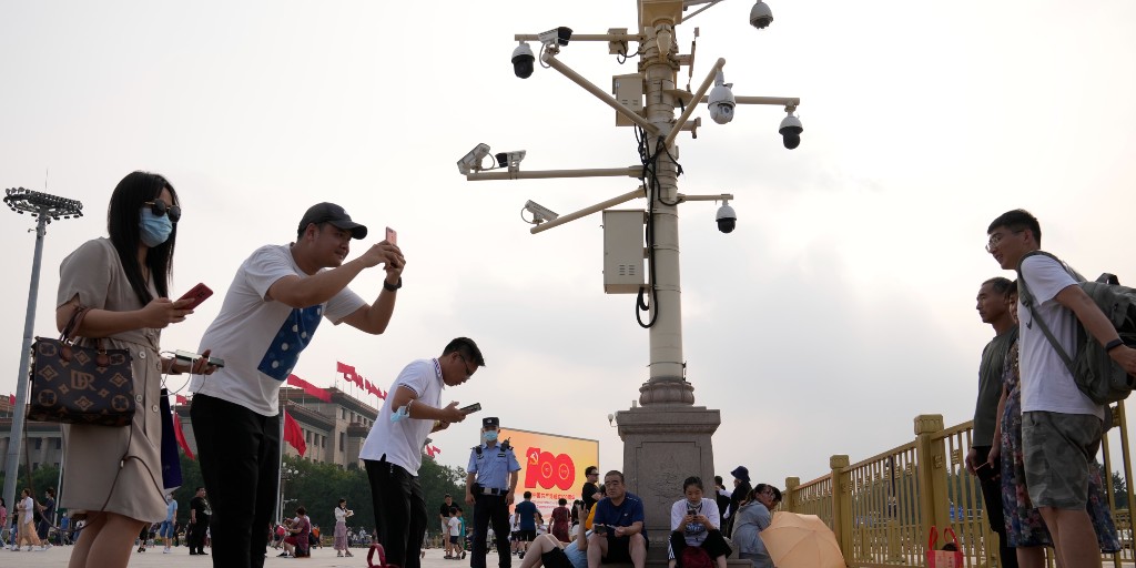 Besökare tar bilder på Himmelska fridens torg, under en mängd övervakningskameror.