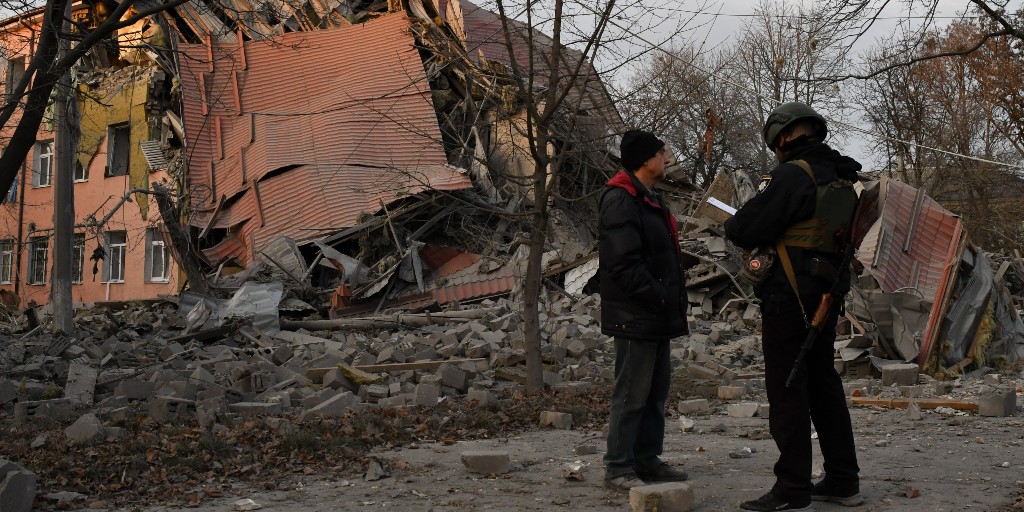 En polis och en man står framför en skola i Kramatorsk som förstörts i en rysk attack.