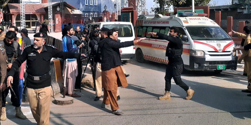 Poliser flyttar folk för att låta ambulanser komma fram efter vad som rapporteras vara en självmordsattack mot en moské i Peshawar i Pakistan på måndagen.