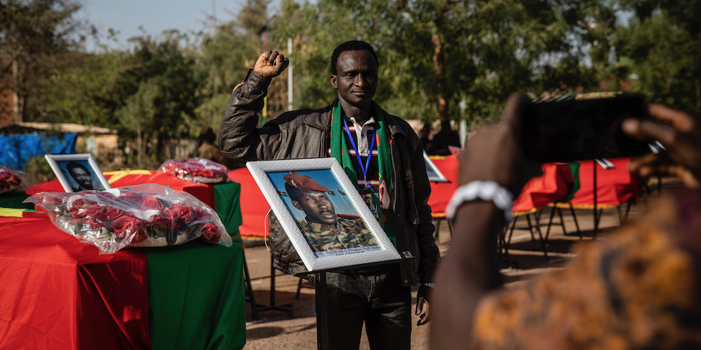 En man poserar för en bild stående bredvid kistan som innehåller kvarlevorna från Burkina Fasos revolutionäre ledare Thomas Sankara i samband med dennes återbegravningsceremoni i Ougadougou torsdagen den 23 februari.