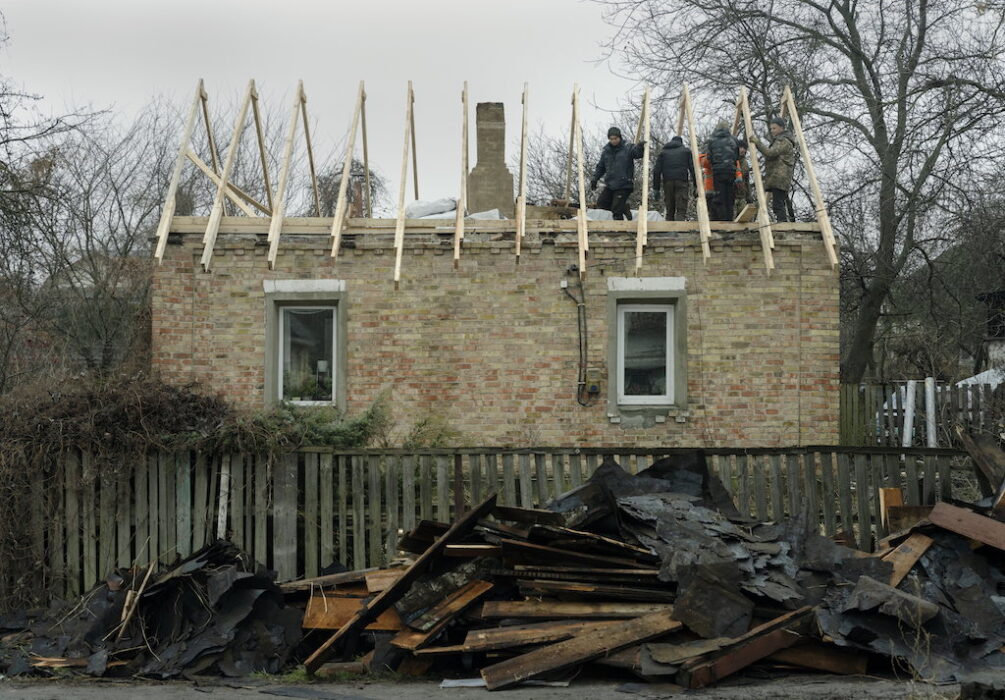 Frivilliga hjälper till att bygga nytt tak på ett skadat hus som ligger vid huvudgatan i Butja, en förstad till Ukrainas huvudstad Kiev