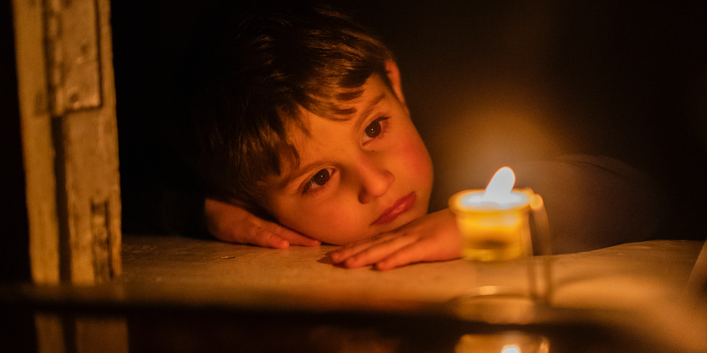 En pojke tittar på ett ljus i försök att värma sig i Stepanakert, huvudstad i regionen Nagorno-Karabach i januari 2023.
