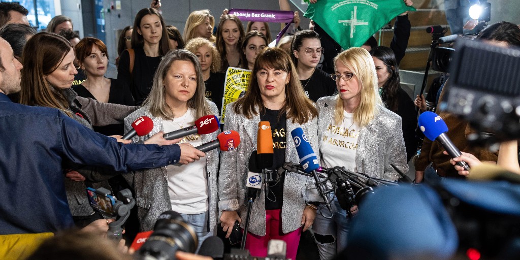 Justyna Wydrzyńska (i mitten) talar med reportrar i Warszawa på tisdagen i samband med att hon dömdes för att ha hjälpt en kvinna som befann sig i en våldsam relation med abortpiller.