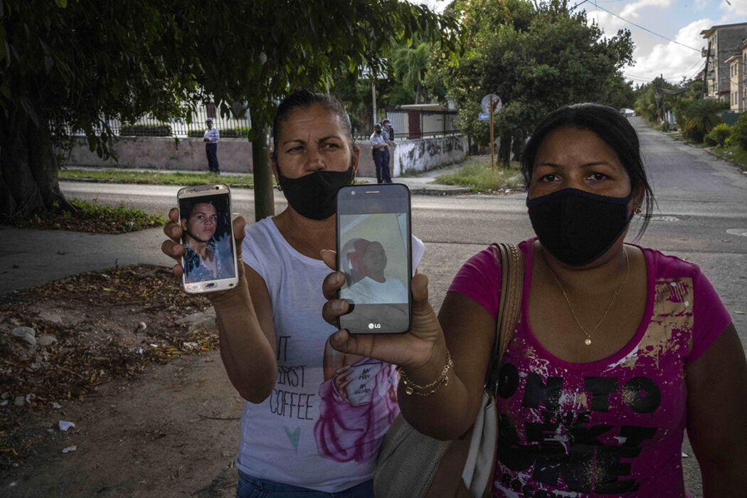 Servilia Pedroso, till höger, mamma till den 18-åriga studenten Eloy Barbaro Cardoso, och Yaquelin Cruz mamma till Dariel Cruz, visar bilderna på dem som greps under protesterna den 11 juli, framför domstolsbyggnaden där de ställs inför rätta