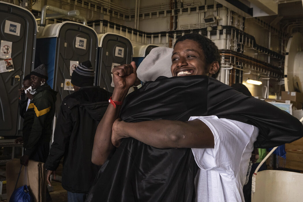 Ahmed, en eritreansk man född i Sudan, firar med en annan överlevande påGeo Barents efter att ha räddats den 6 januari 2023