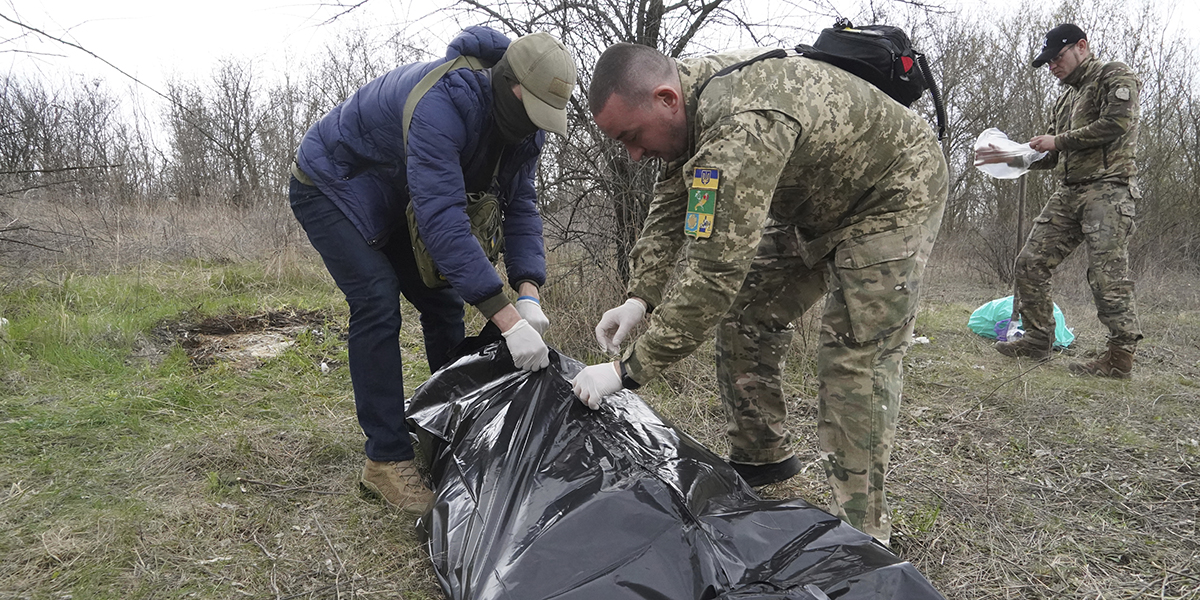 Ukrainska militärer packar den döda kroppen av en rysk soldat, dödad i strid i Charkiv-regionen, Ukraina, lördagen den 8 april 2023.