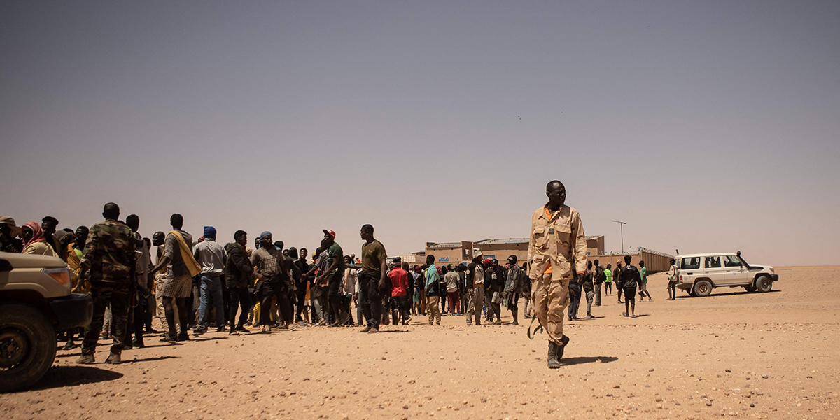 Soldater har ett vakande öga kring samlade migranter i det nigeriska gränssamhället Assamaka.