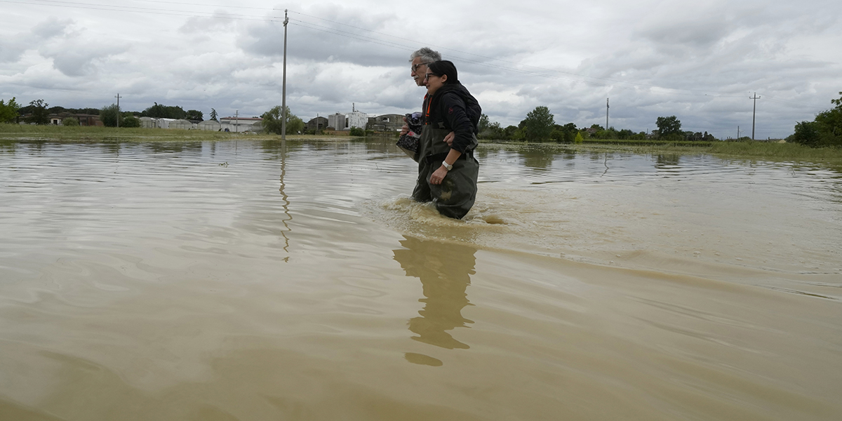 Ett par går på en översvämmad väg i Lugo, Italien, torsdagen den 18 maj 2023.