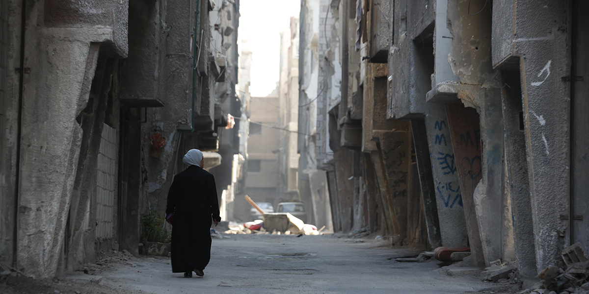 En kvinna går genom Yarmouk-lägret i Damaskus som har gått igenom hårda strider under inbördeskriget, november 2022.