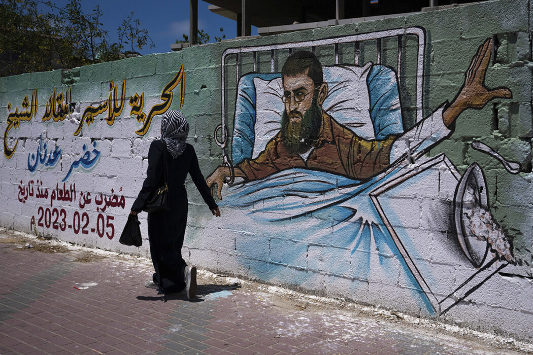En palestinsk kvinna går förbi en väggmålning av Khader Adnan, en palestinsk islamisk jihad-militant som dog i israeliskt fängelse efter en nästan tre månader lång hungerstrejk, i Gaza City, tisdagen den 2 maj 2023