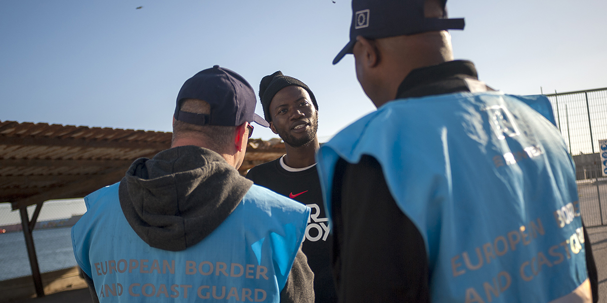 En migrant som räddats av spanska sjöfartsmyndigheter pratar med två medlemmar av Europeiska gräns- och kustbevakningsbyrån (Frontex) när han anländer till hamnen i Motril i Granada, Spanien, februari 2020.