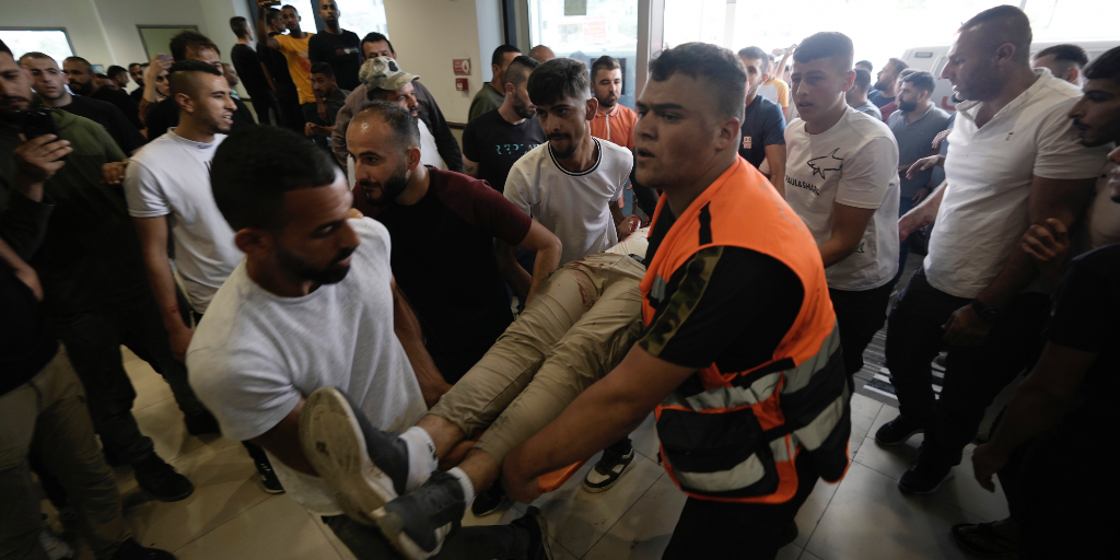 En skadad palestinier bärs in på ett sjukhus i Jenin, strider mellan den israeliska armén och väpnade palestinier pågick i upp till åtta timmar på måndagen.