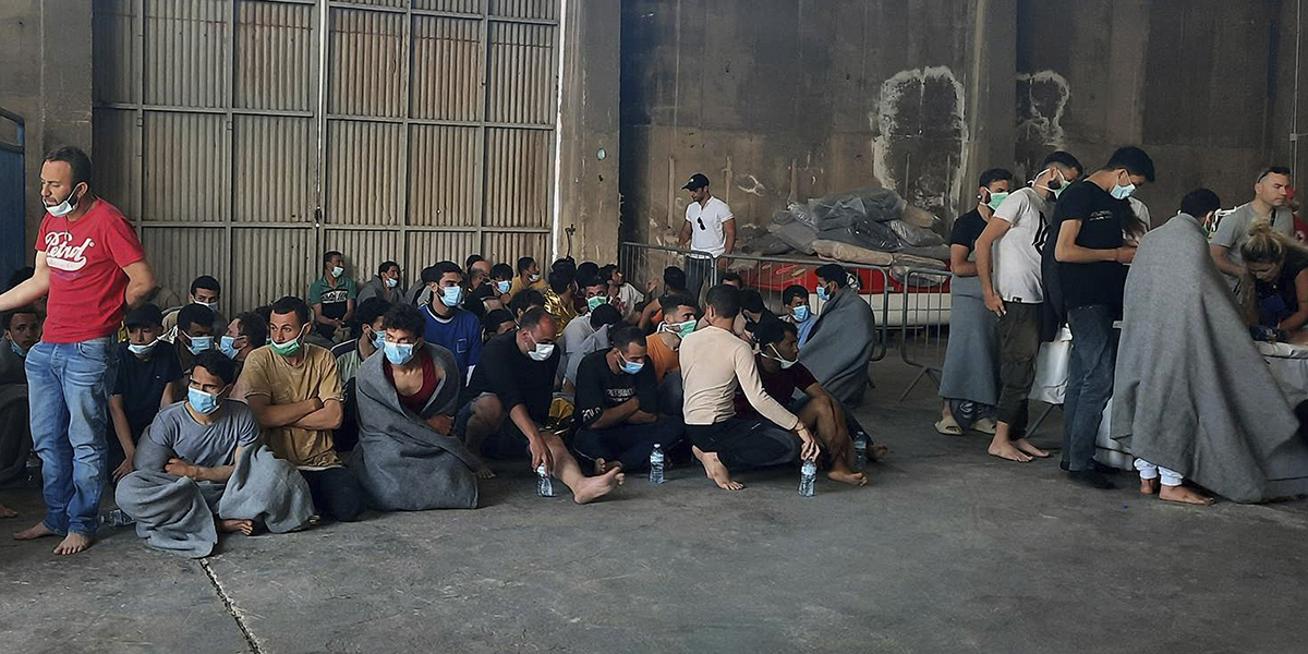 Överlevande från ett skeppsvrak sitter vid ett lager i hamnen i staden Kalamata, cirka 240 kilometer sydväst om Aten onsdagen den 14 juni 2023.