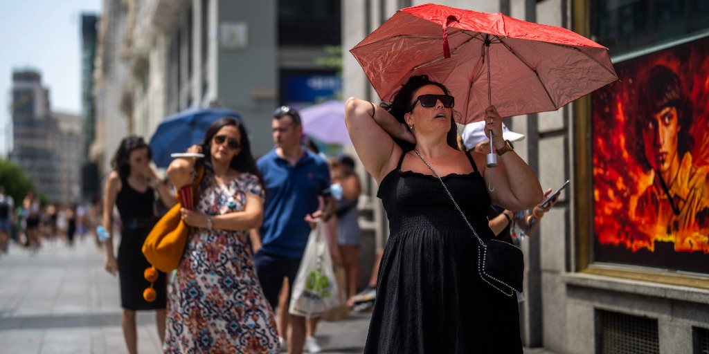 En kvinna håller upp ett paraply för att skydda sig mot solen i Madrid i Spanien i juli 2022 då landet uppmätte rekordtemperaturer.