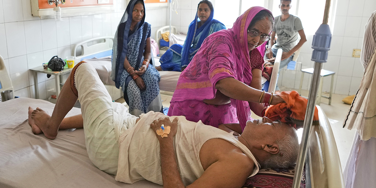 Shiela Mishra torkar huvudet på sin bror för att svalka honom från värmeböljan, distriktssjukhuset i Ballia, delstaten Uttar Pradesh, Indien, måndagen den 19 juni 2023.
