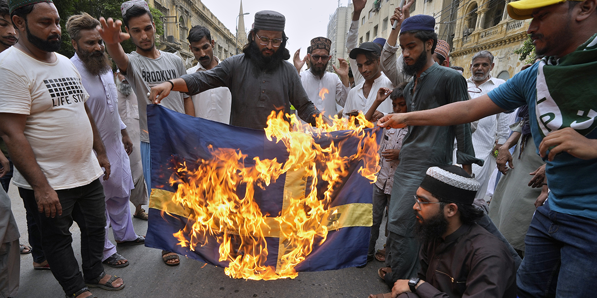 Anhängare till ett radikalt islamistparti i Pakistan bränner ett tygstycke som ska föreställa en svensk flagga i Karachi i fredags förra veckan.