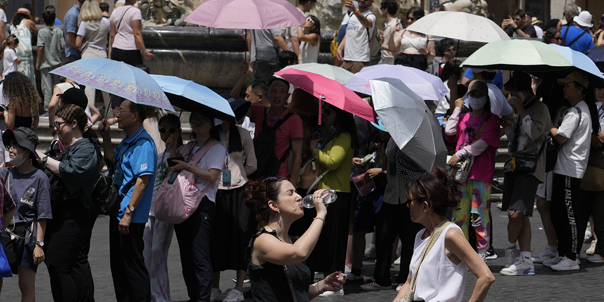 Turister använder paraplyer för att skydda sig från solen när de köar för att komma in i Pantheon i Rom, lördagen den 8 juli 2023.