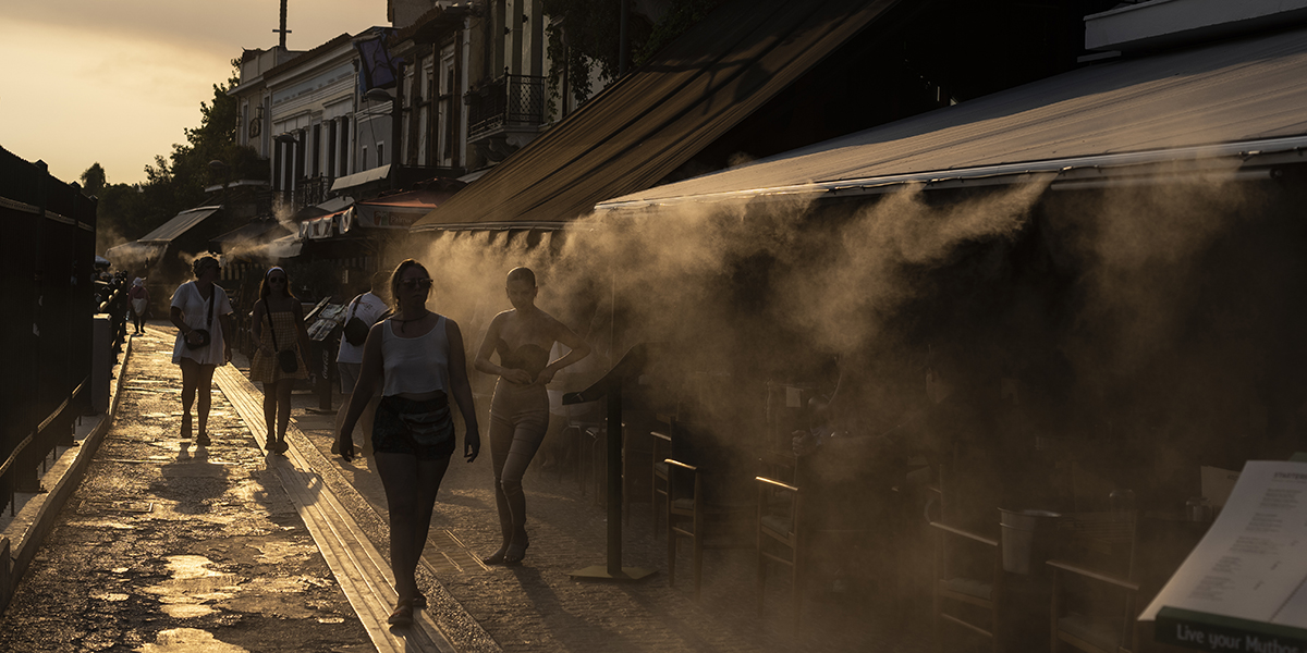 Människor låter sig svalkas av en dimmaskin i Aten, torsdagen den 20 juli 2023.