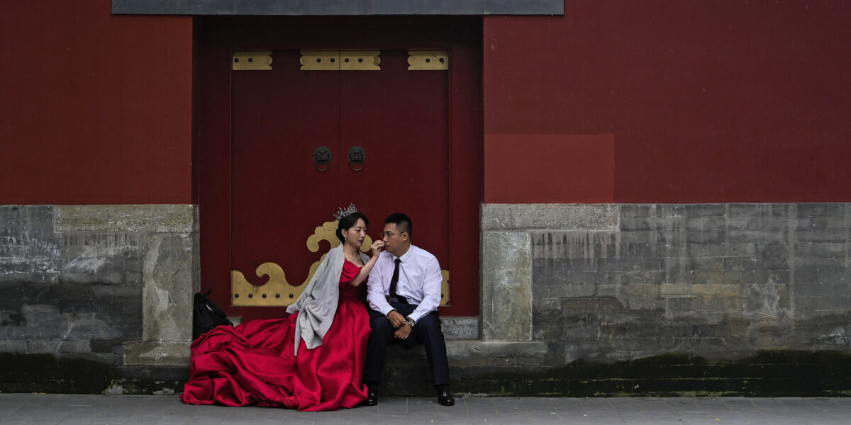 En brud torkar av sin brudgums ansikte medan de väntar på sin tur för ett bröllopsfoto,  i Peking, oktober 2021.