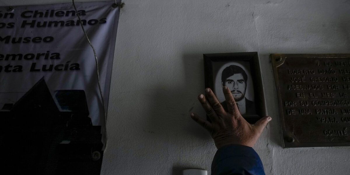 En man placerar ett porträtt av Dario Hernandez, en politisk fånge som avrättades under diktaturen i Chile, vid den före detta Santa Lucia-kliniken som var platsen för ett hemligt internerings- och tortyrcenter, 28 augusti 2023.