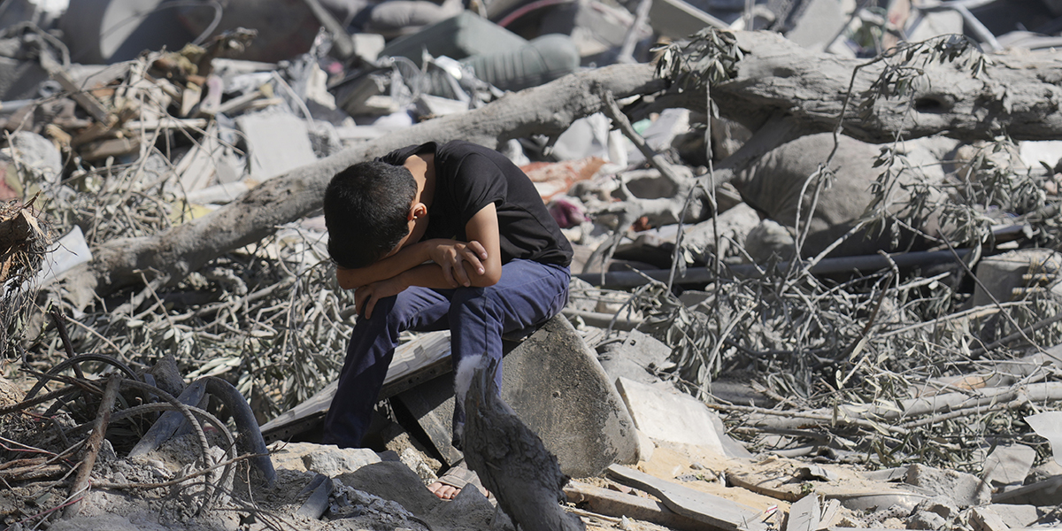 En palestinsk pojke sitter på spillrorna av byggnaden som förstördes i ett israeliskt luftangrepp i flyktinglägret Bureij på Gazaremsan, onsdagen den 18 oktober 2023.