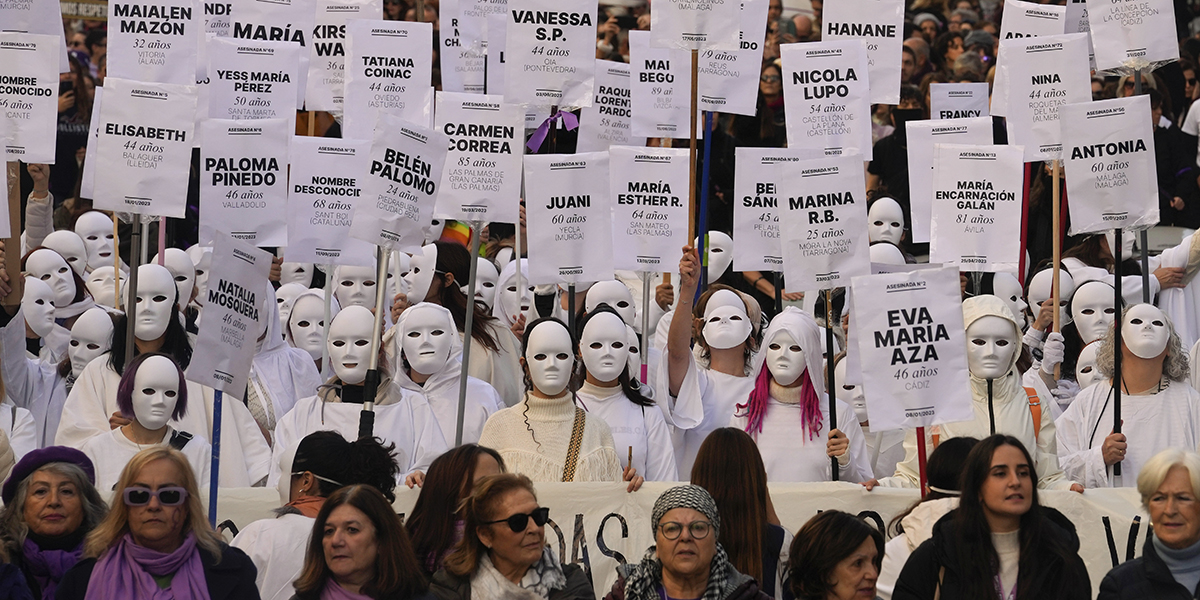 Kvinnor med masker marscherar med plakat med namnen på kvinnor som har dödats, under den internationella dagen för avskaffande av våld mot kvinnor, i Madrid, Spanien, lördagen den 25 november 2023.