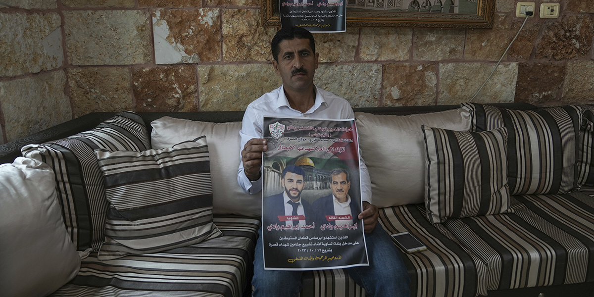 Palestiniern Abdelazim Wadi, 50, håller upp en plansch som tryckts till minne av hans bror och brorson som dödades av israeliska bosättare under en begravningsprocession i byn Qusra på Västbanken den 12 oktober.