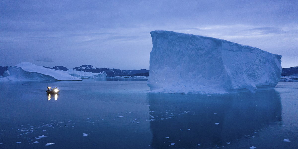 Isberg i Arktis och liten båt.