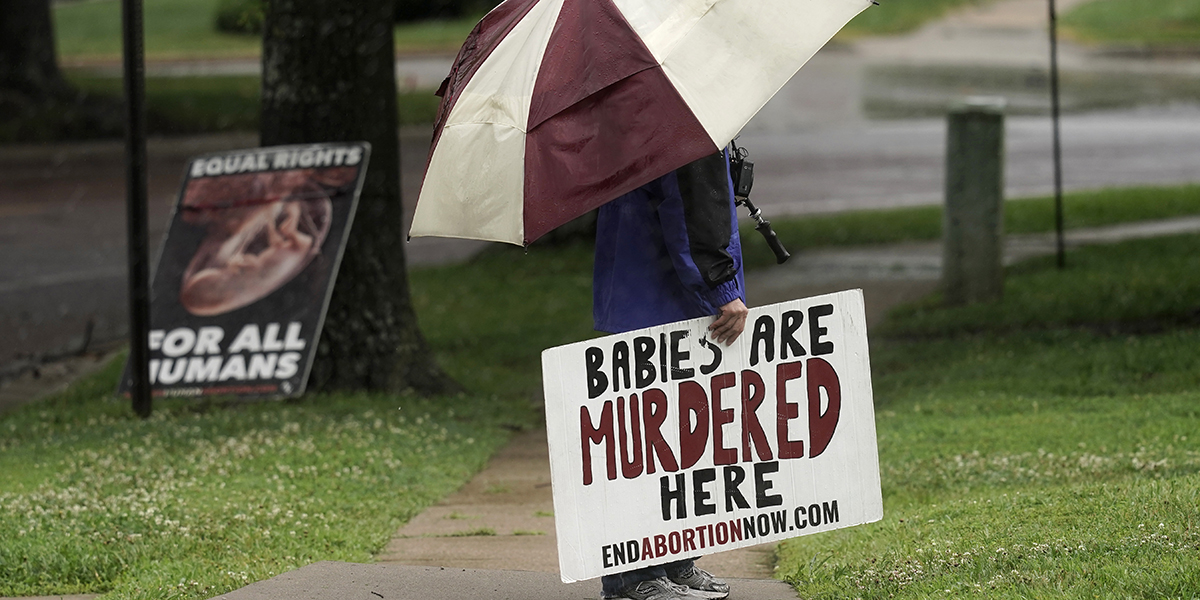Anti-abort aktivist står under paraply med plakat