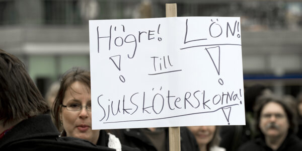 två kvinnor med plakat i protest mot låga kvinnolöner