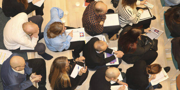 bild ovanifrån på människor som sitter och antecknar