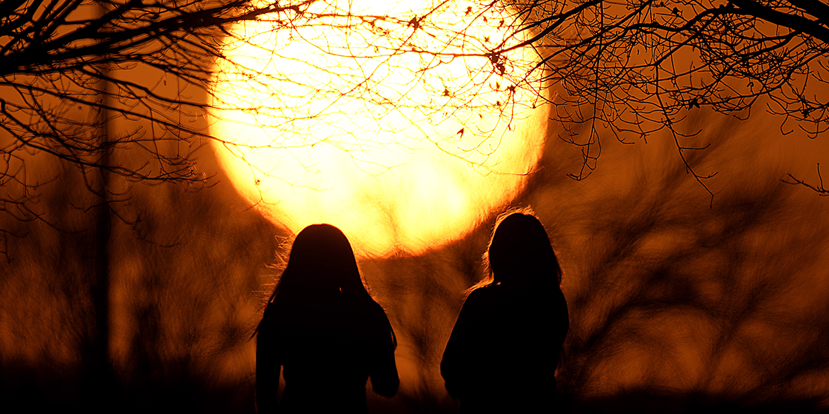Solnedgång med två människor i silhuett