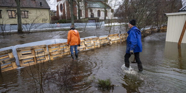 två personer vadar i vatten från översvämning