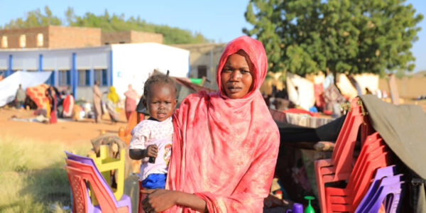 Kvinna i rött håller i ett barn.