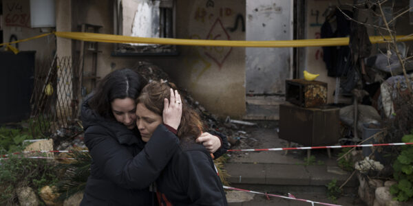 Amit Soussana,kramas om av en vän framför rasmassor