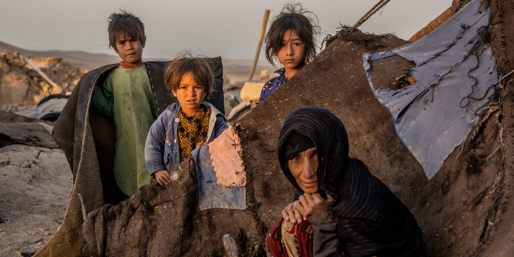 En kvinna och tre barn vid ett slitet tält i Afghanistan.