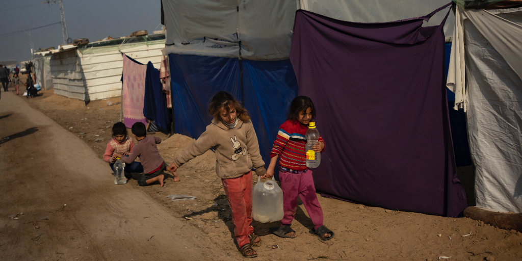Barn fyller på och hämtar vatten intill tält i Gazaremsan.