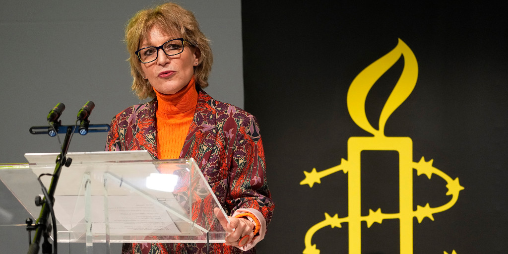 Agnes Callamard bredvid Amnesty Internationals logga med taggtråd kring stearinljus.