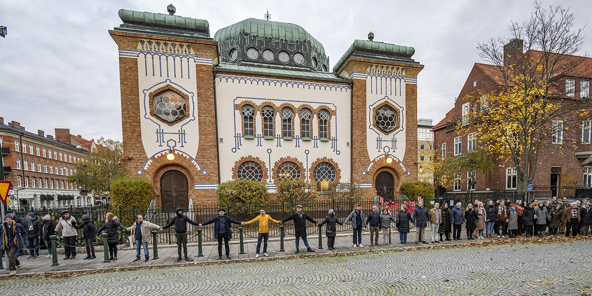 Människor hand i hand bildar en ring runt Synagogan i Malmö under en stödmanifestation för Malmös judar den 11 november 2023.