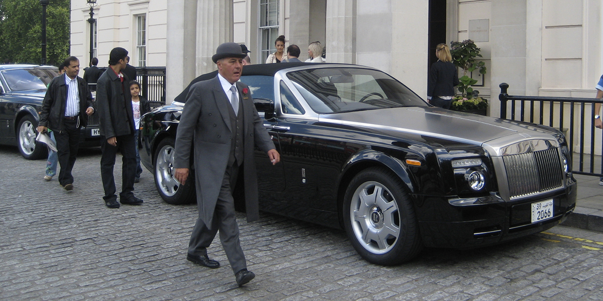 man i hatt framför Rolls Royce