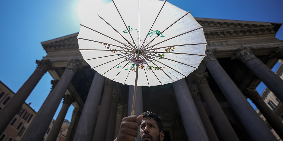 man skyddar sig med paraply mot solen