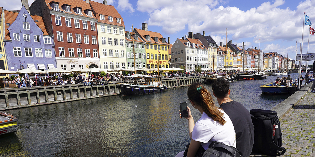 Två turister sitter på en kaj